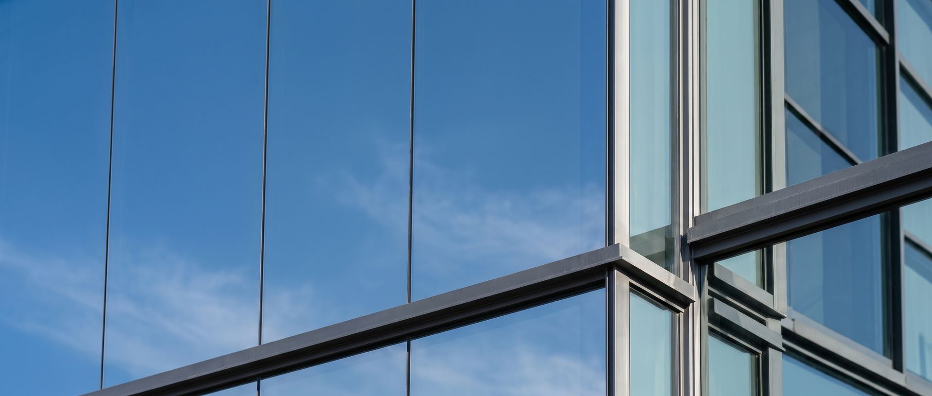 Fachada corporativa de cristal y acero reflejando el cielo